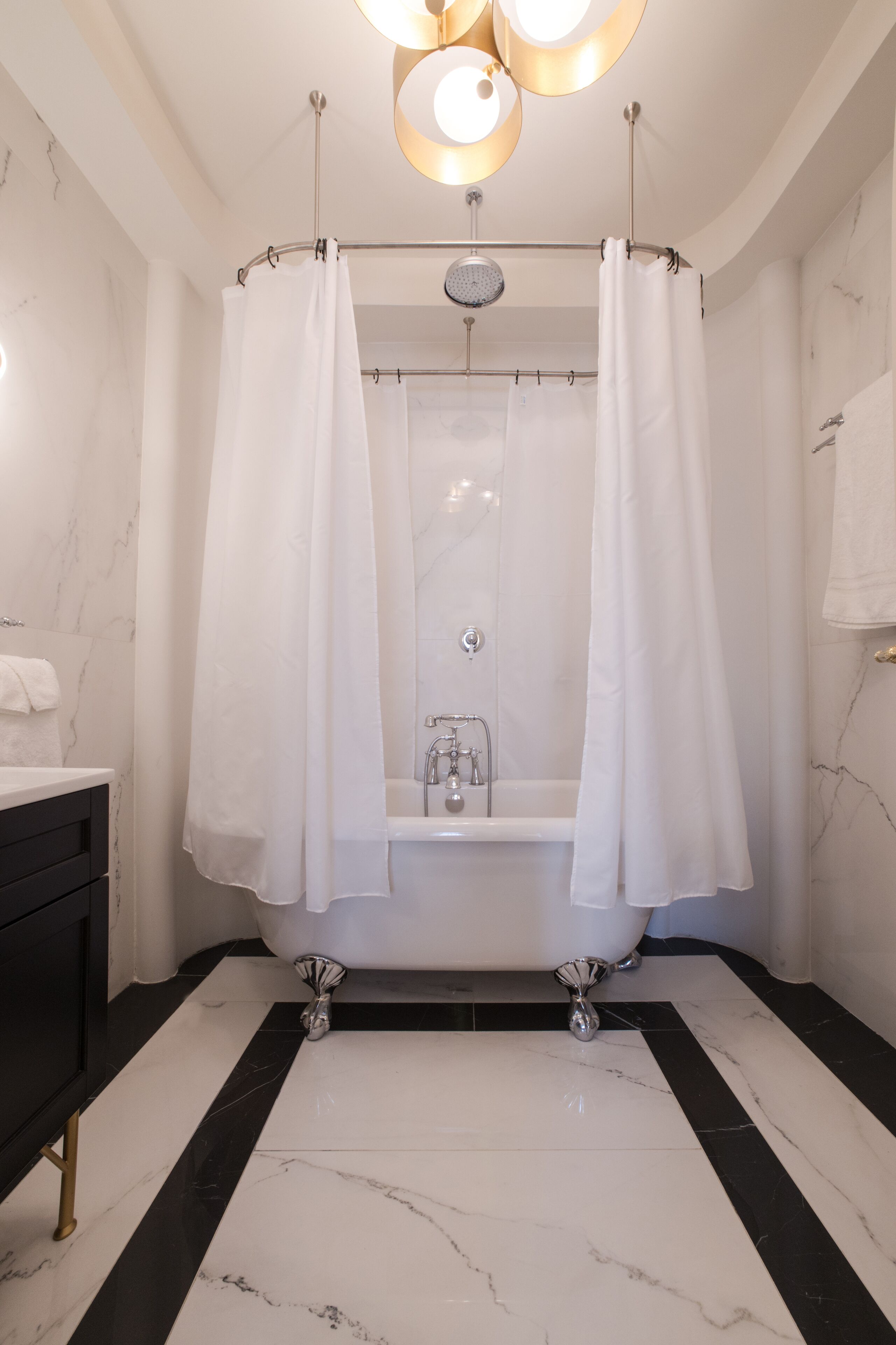 Un baño moderno con una bañera independiente, suelo de mármol y cortina de ducha.