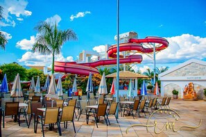 Un parc aquatique doté de nombreux toboggans, d’un espace extérieur aménagé et d’un bâtiment portant l’inscription « SANITAIRES ».