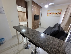 A modern kitchen with a granite countertop, a built-in oven, and a dining area with a black sofa.