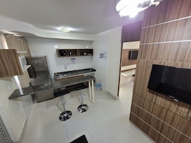 Una cocina moderna con horno empotrado, un lavamanos y un televisor montado en la pared.