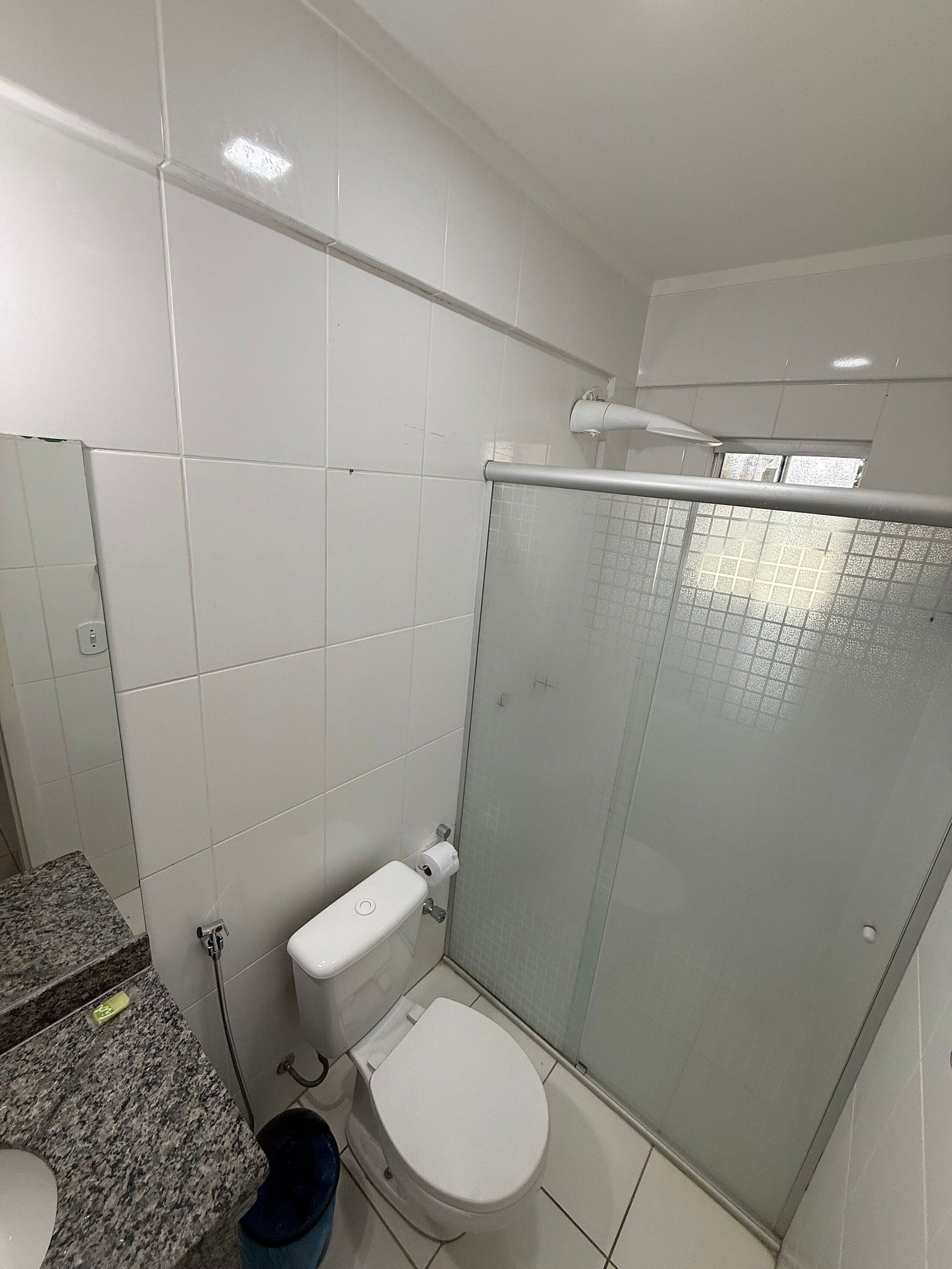 Un baño con inodoro, ducha con puerta de cristal y paredes de azulejos.
