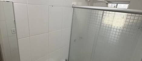 A bathroom with a toilet, a shower with a glass door, and tiled walls.