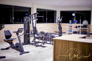 A gym with exercise equipment, a bench, and a wall-mounted rack with weights.
