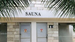 Un edificio con un cartel que dice 'SAUNA' sobre dos puertas cerradas con contraventanas.