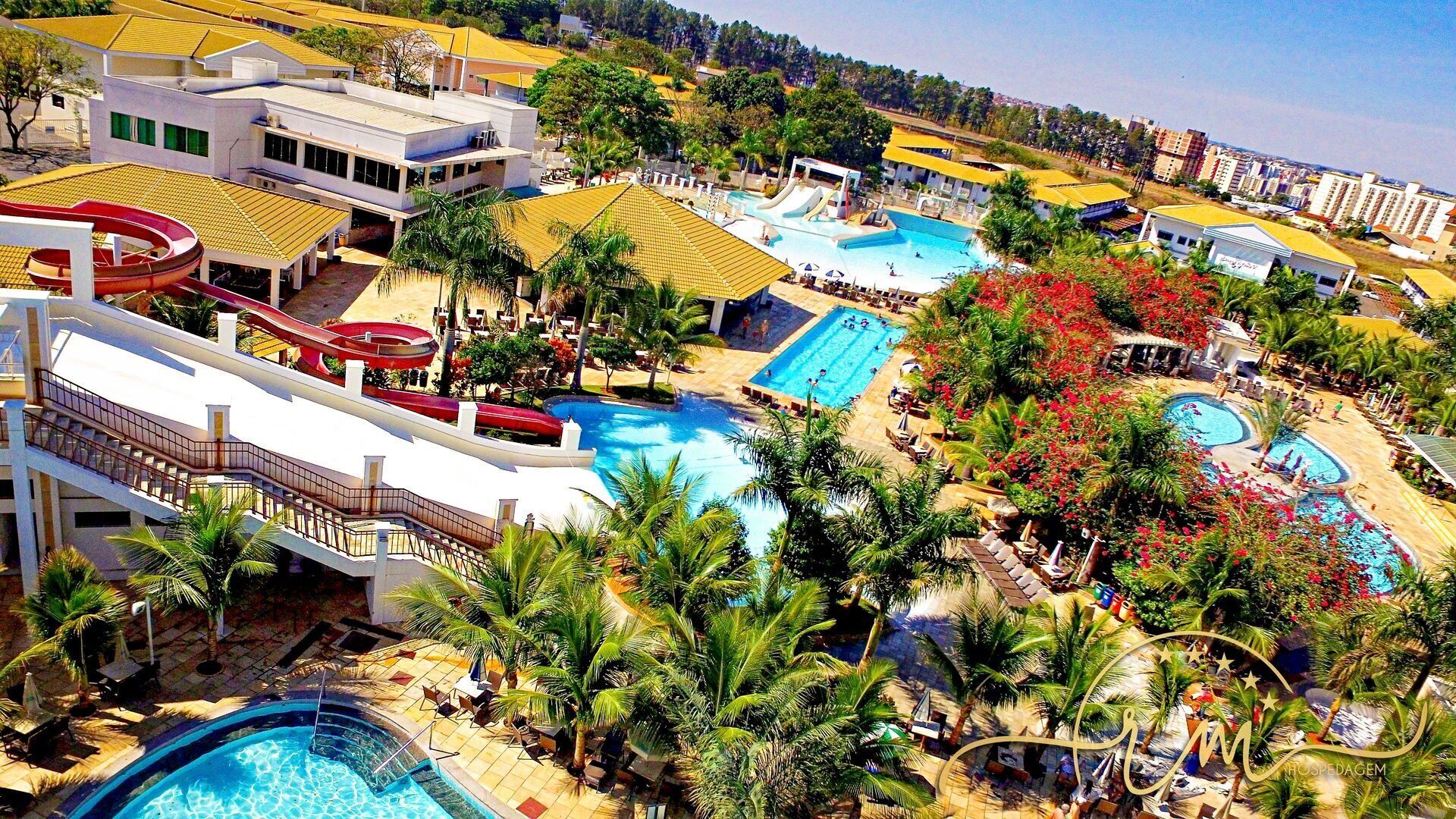 Een resort met meerdere zwembaden, glijbanen en palmbomen.