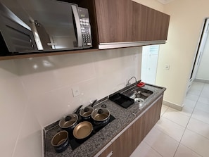 Una cocina equipada con microondas, estufa, fregadero y armarios.