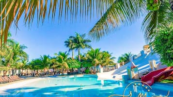 A pool area with palm trees, lounge chairs, and a water slide.