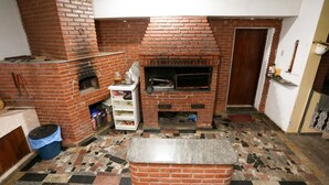 A brick fireplace with a shelf above it, a tiled floor, and a door to the right. - Chácara Bosque dos Pássaros - Santa Isabel (Santa Isabel)