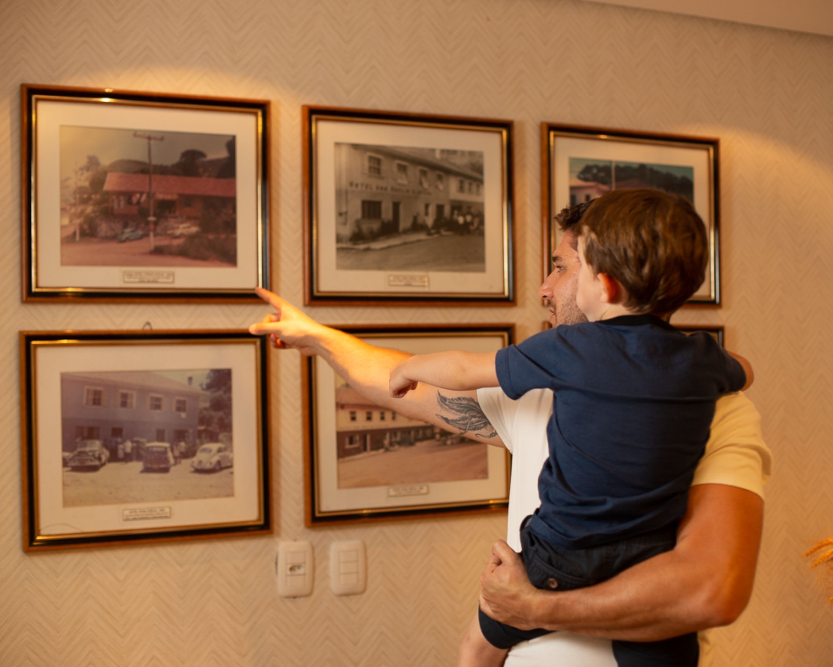 Una persona señala fotografías enmarcadas en una pared.
