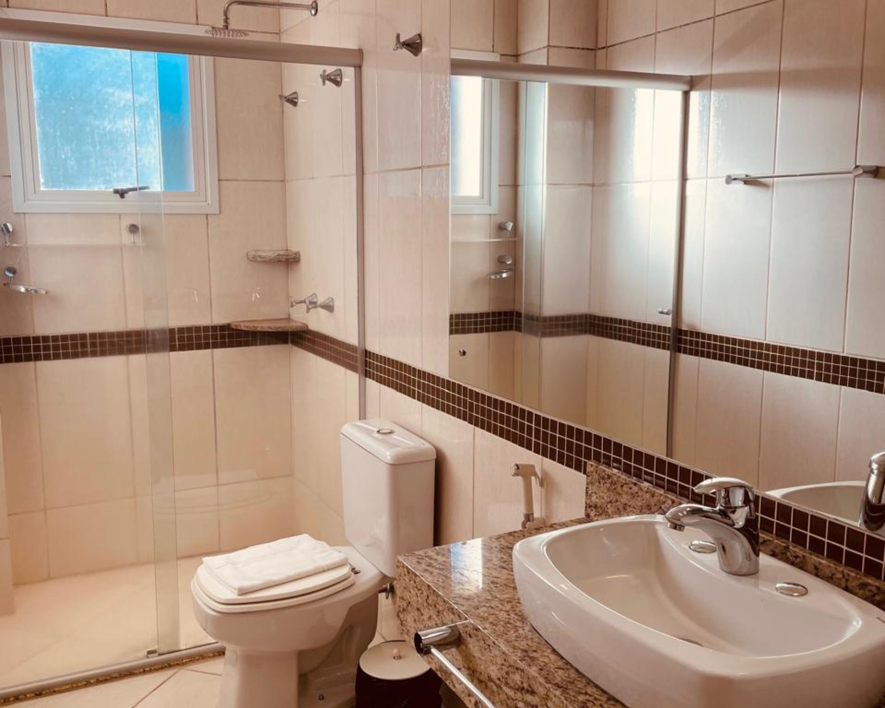 Un baño con inodoro, lavamanos, ducha y ventana.