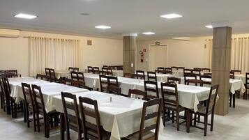 A large, well-lit conference room with multiple tables and chairs, arranged in rows.