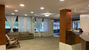 Un hall d’entrée spacieux avec un comptoir d’accueil, un canapé et un fauteuil.