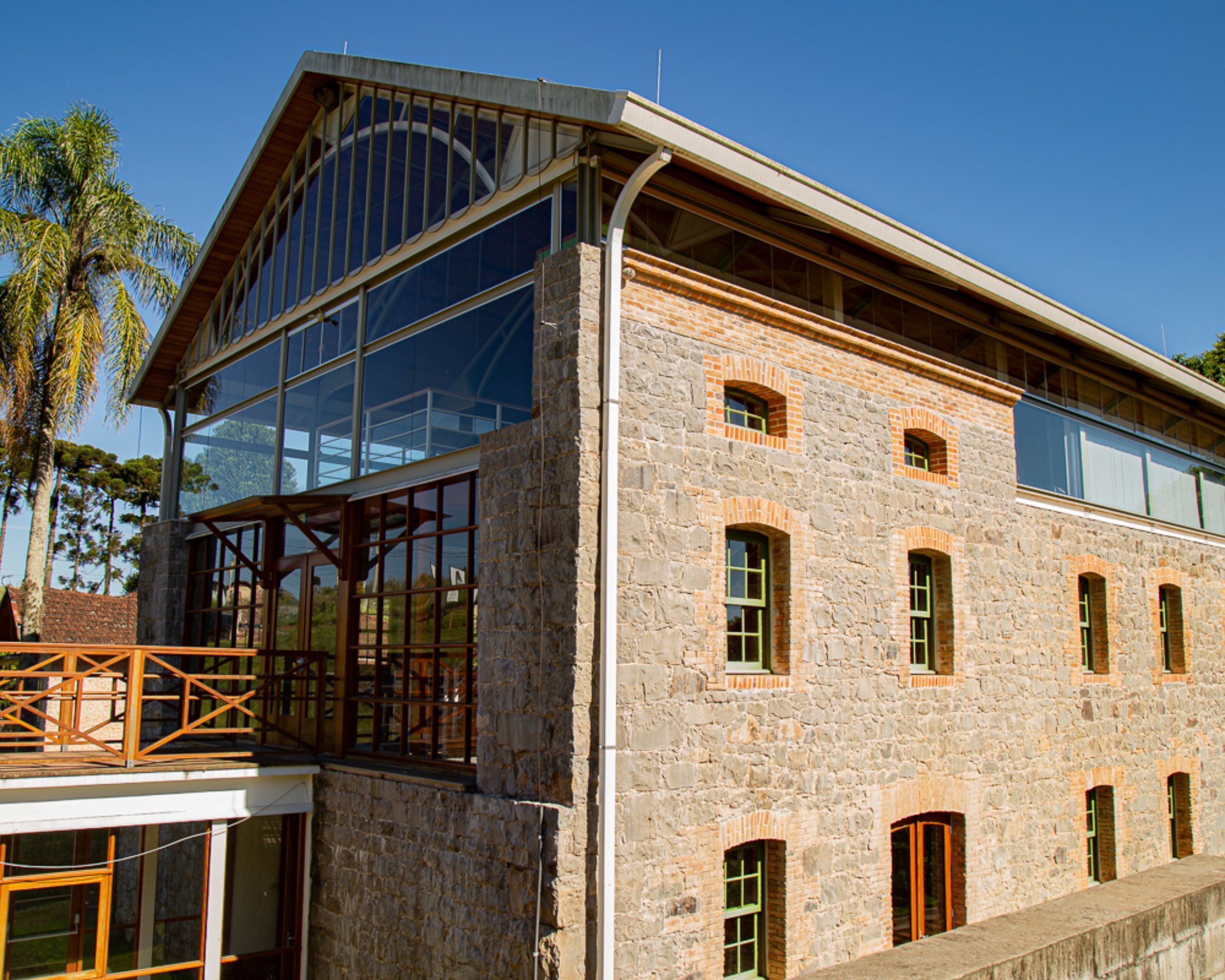 A modern building with large glass windows, stone walls, and multiple doors.