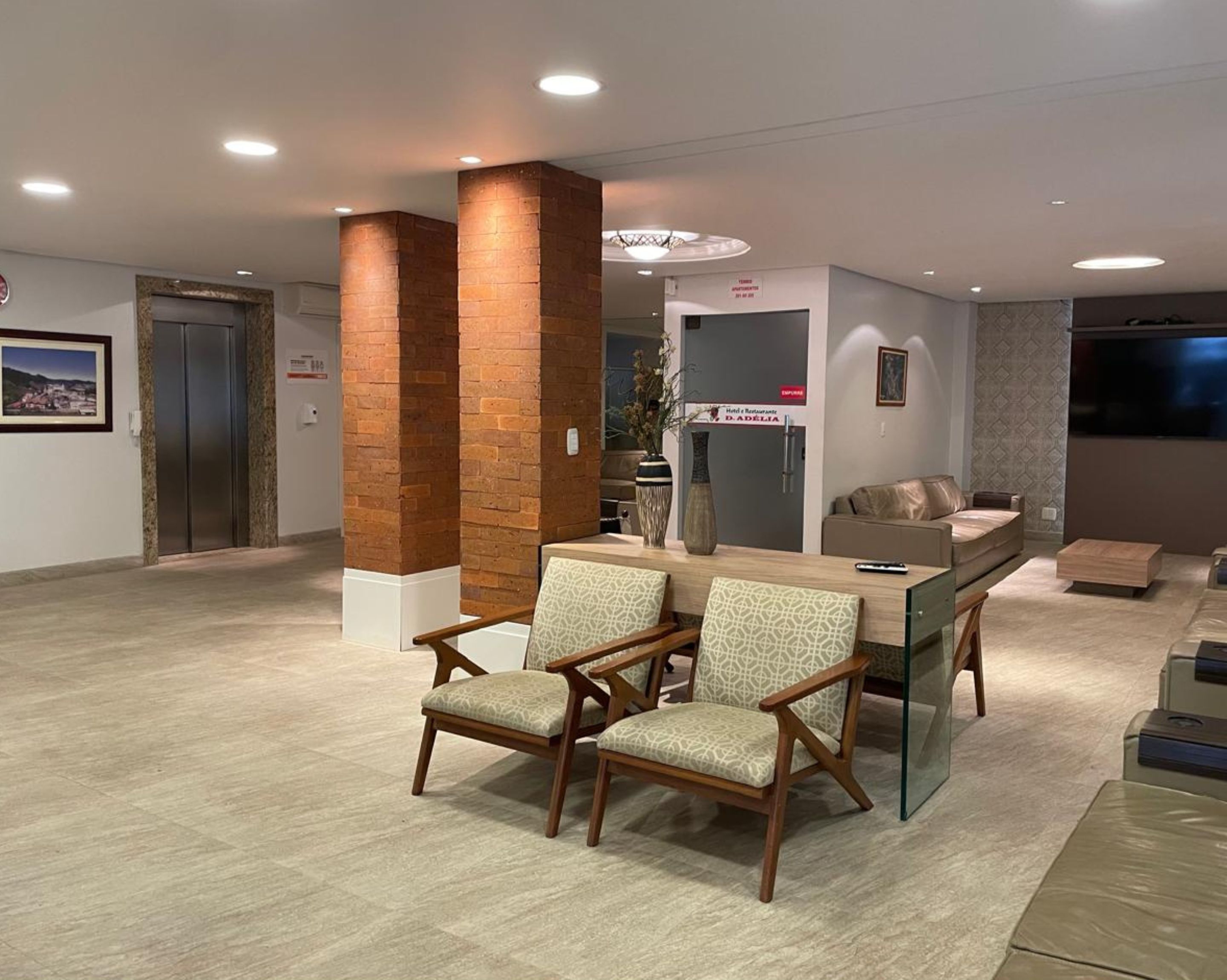 A reception area with a reception desk, two chairs, a sofa, a TV, and a fireplace.