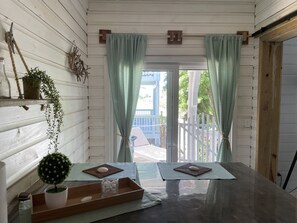 A room with a wooden interior, a glass table with a tray, a potted plant, and a view through a glass door. - Turquesa unit -Great location if you want to stay close to the West Bay beach  (West Bay)