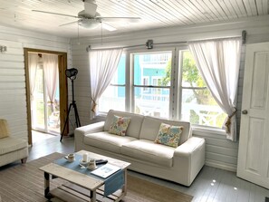 Relax in this spacious room with a high ceiling, featuring a large window and a comfortable sofa.