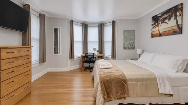 Une chambre à coucher avec un lit, un bureau, une chaise, une commode et un tableau.
