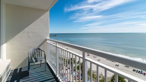Un balcon avec vue sur une plage et l’océan.