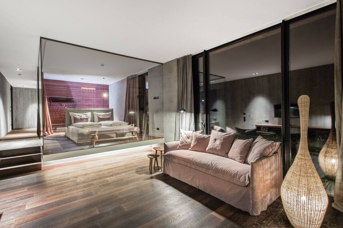 A modern living room with a sofa, a glass partition, and a large vase.