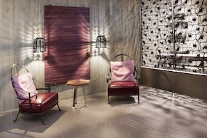 A modern room with two leather chairs, a small wooden table, and a large abstract wall art piece. - Senses Violett Suites - Adults only (Zell am See)