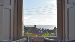 Ein Zimmer mit Meerblick durch ein Fenster, eine Weinflasche und ein Glas auf einem Tisch.