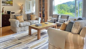Un salon spacieux avec une grande fenêtre, une bibliothèque et un coin salon confortable.