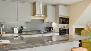 Una cocina moderna con encimera de granito, electrodomésticos de acero inoxidable y horno empotrado.