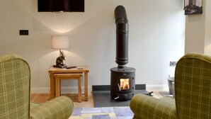 Una sala de estar con chimenea, televisor y una mesa con una lámpara y una figurita de conejo.
