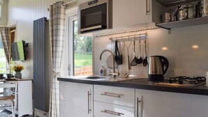 Une cuisine moderne avec des meubles blancs, un évier en acier inoxydable, un four à micro-ondes et une cuisinière à gaz.