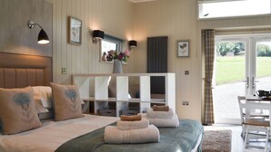 Une chambre à coucher avec un lit, des tables de chevet, un miroir, une fenêtre et une vue sur l’extérieur.