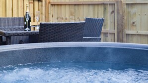 A hot tub with wicker chairs and a bottle of champagne. - 0 bedroom accommodation in Brocklebank, near Caldbeck and Uldale (Brocklebank, near Caldbeck and Uldale)