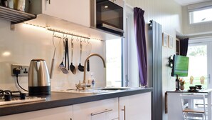 A modern kitchen with a stainless steel kettle, a range hood, and a window with purple curtains. - 0 bedroom accommodation in Brocklebank, near Caldbeck and Uldale (Brocklebank, near Caldbeck and Uldale)