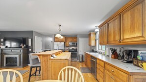 A modern kitchen with wooden cabinets, stainless steel appliances, and a central island with seating. - Steps to the Beaches of Lake Erie 4BR, 3BA Home (Dunkirk)