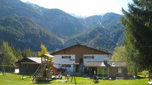 Een lodge met een speelruimte, een overdekt zitgedeelte en uitzicht op bergen.