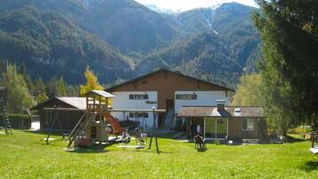 Un chalet doté d’un espace de jeux, d’un coin salon couvert et offrant une vue sur les montagnes.