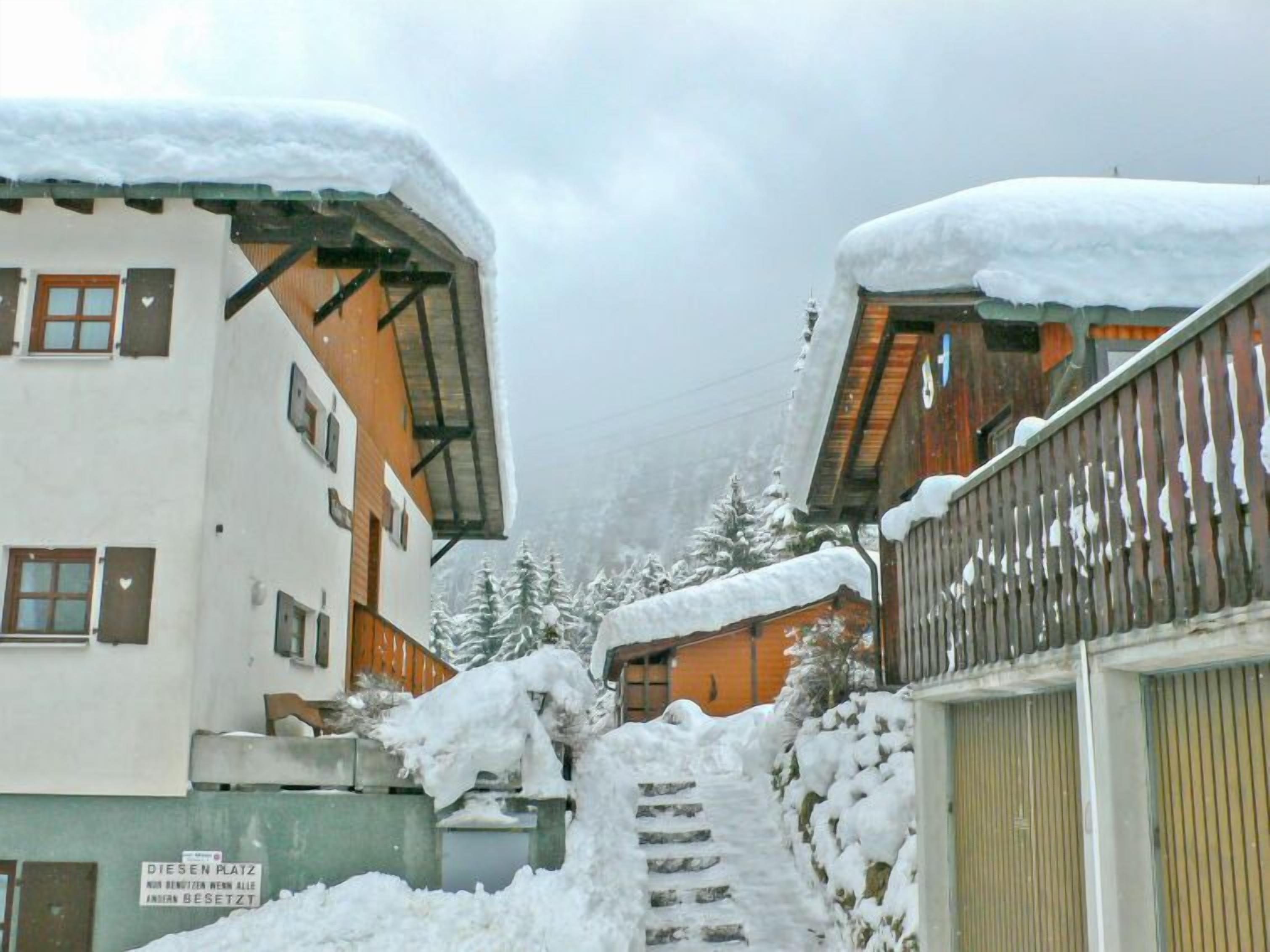 Un bâtiment recouvert de neige, avec un escalier en bois menant à un garage.