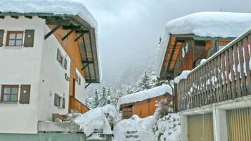 Un bâtiment recouvert de neige, avec un escalier en bois menant à un garage.
