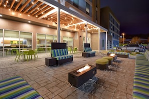 Un patio al aire libre con mobiliario, una chimenea y una sección cubierta con cocina de fondo.