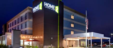 A hotel with a prominent "HOME 2" sign, outdoor seating area, and a covered entrance.