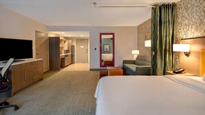 A hotel room with a bed, desk, chair, TV, and a small kitchenette. - Home2 Suites by Hilton Eau Claire South (Eau Claire)