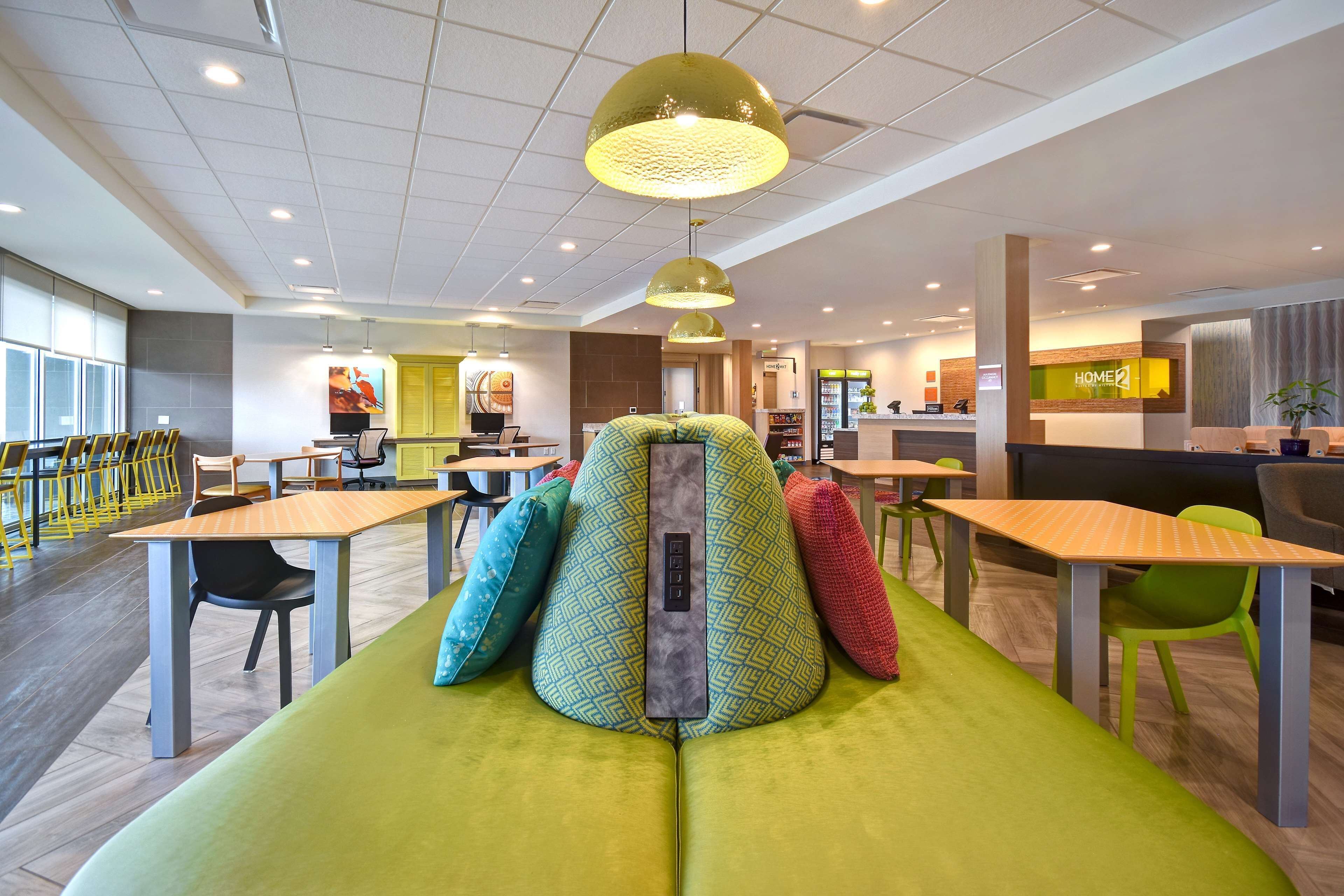 Un intérieur moderne avec un canapé vert, des tables en bois et des chaises.
