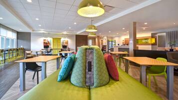 Un intérieur moderne avec un canapé vert, des tables en bois et des chaises.