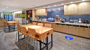 A modern cafe with wooden tables and chairs, a counter with a display case, and a sign reading "inspired table". - Home2 Suites by Hilton Eau Claire South (Eau Claire)