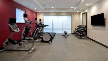 Une salle de sport équipée de tapis de course, de vélos elliptiques et de bancs de musculation.