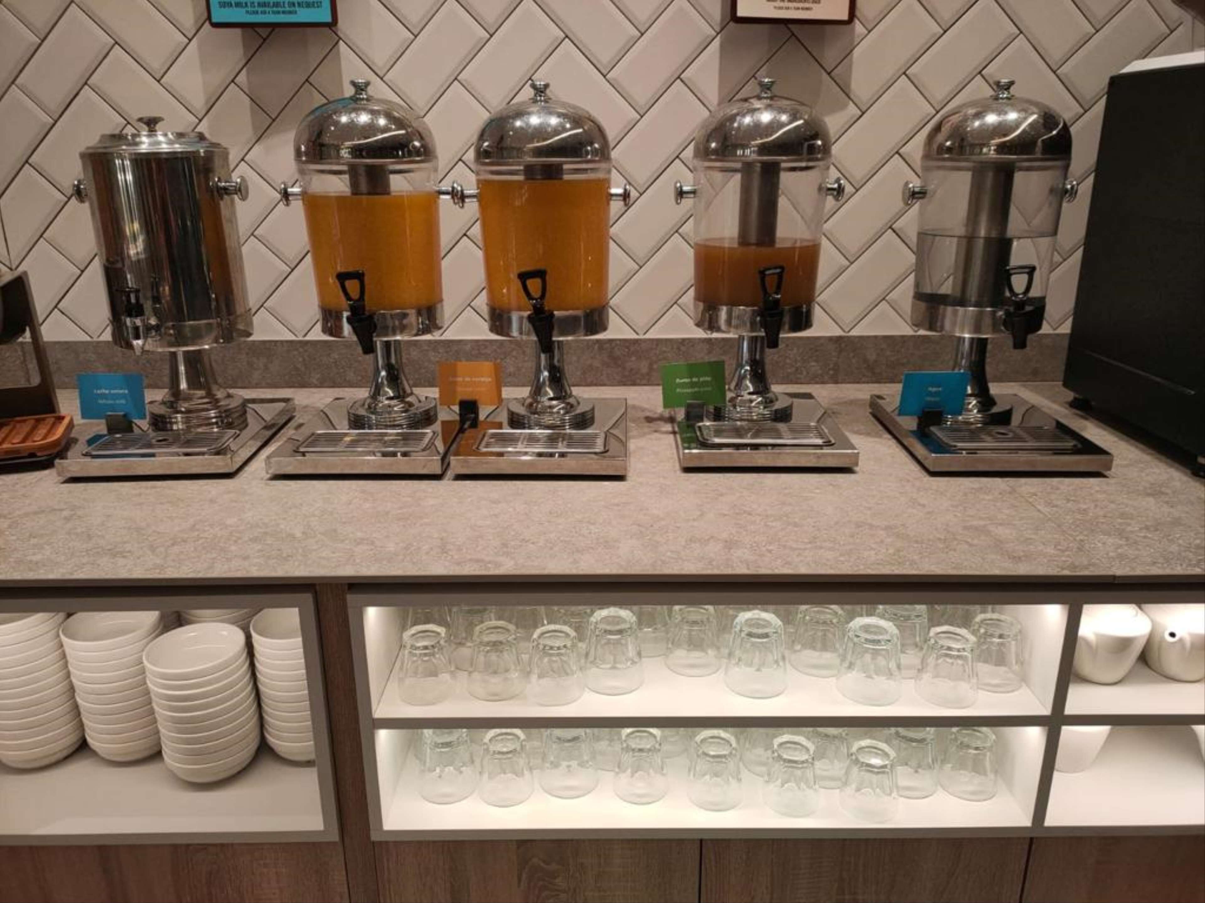 Una estación de café con cuatro dispensadores, un molinillo y una exhibición de tazas de café.