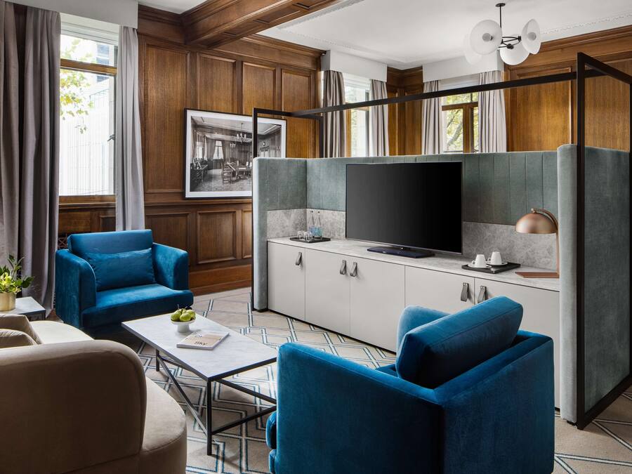 A modern living room with a sofa, armchairs, a coffee table, and a television on a cabinet.