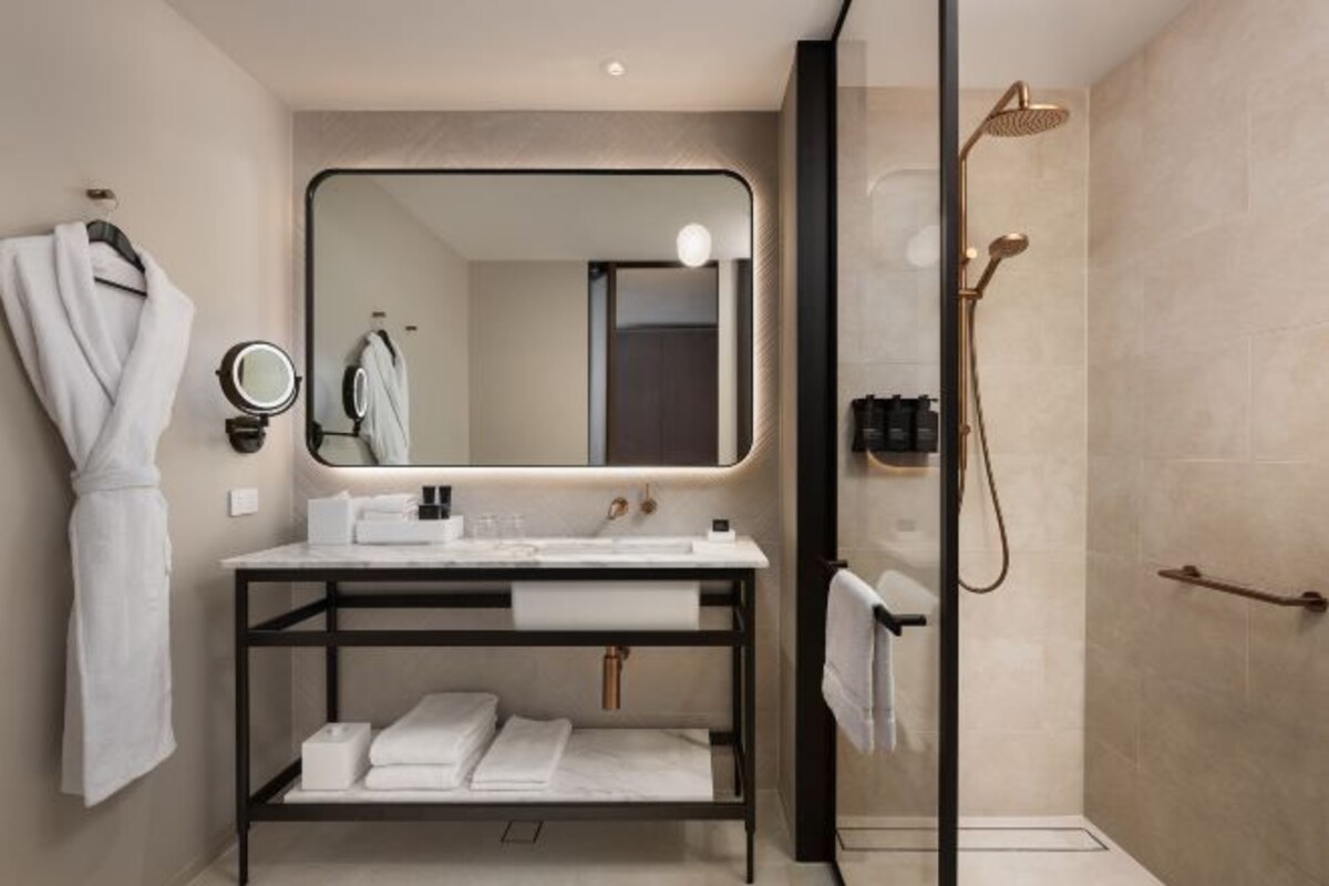 A modern bathroom with a vanity, mirror, and shower.