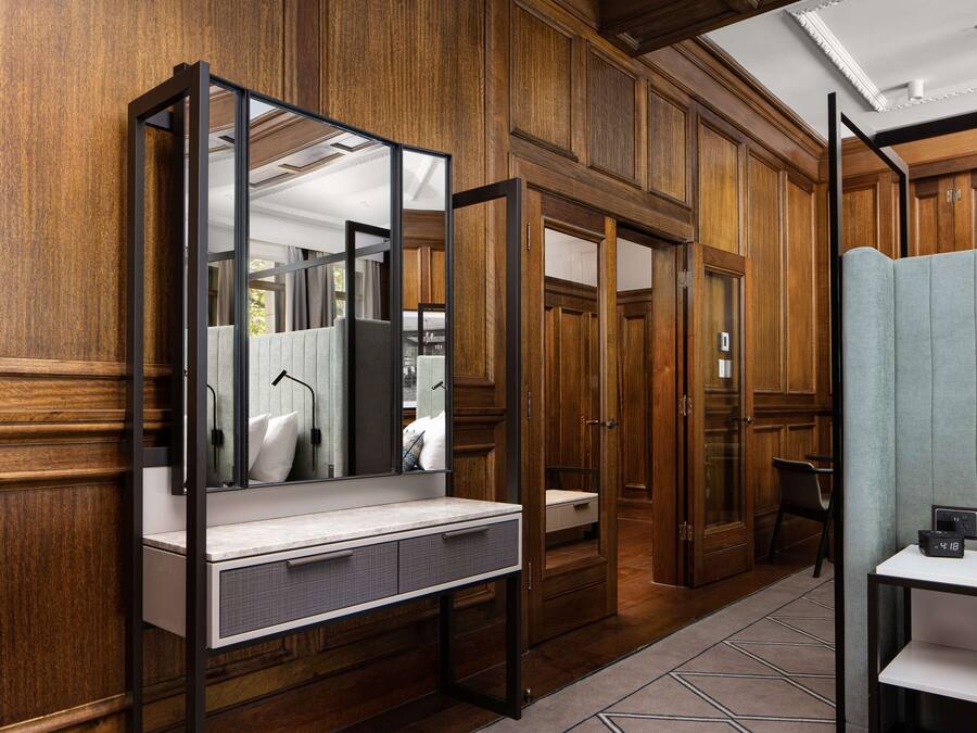 Une salle de bain avec un grand miroir, un lambris en bois, un lavabo et un espace douche.