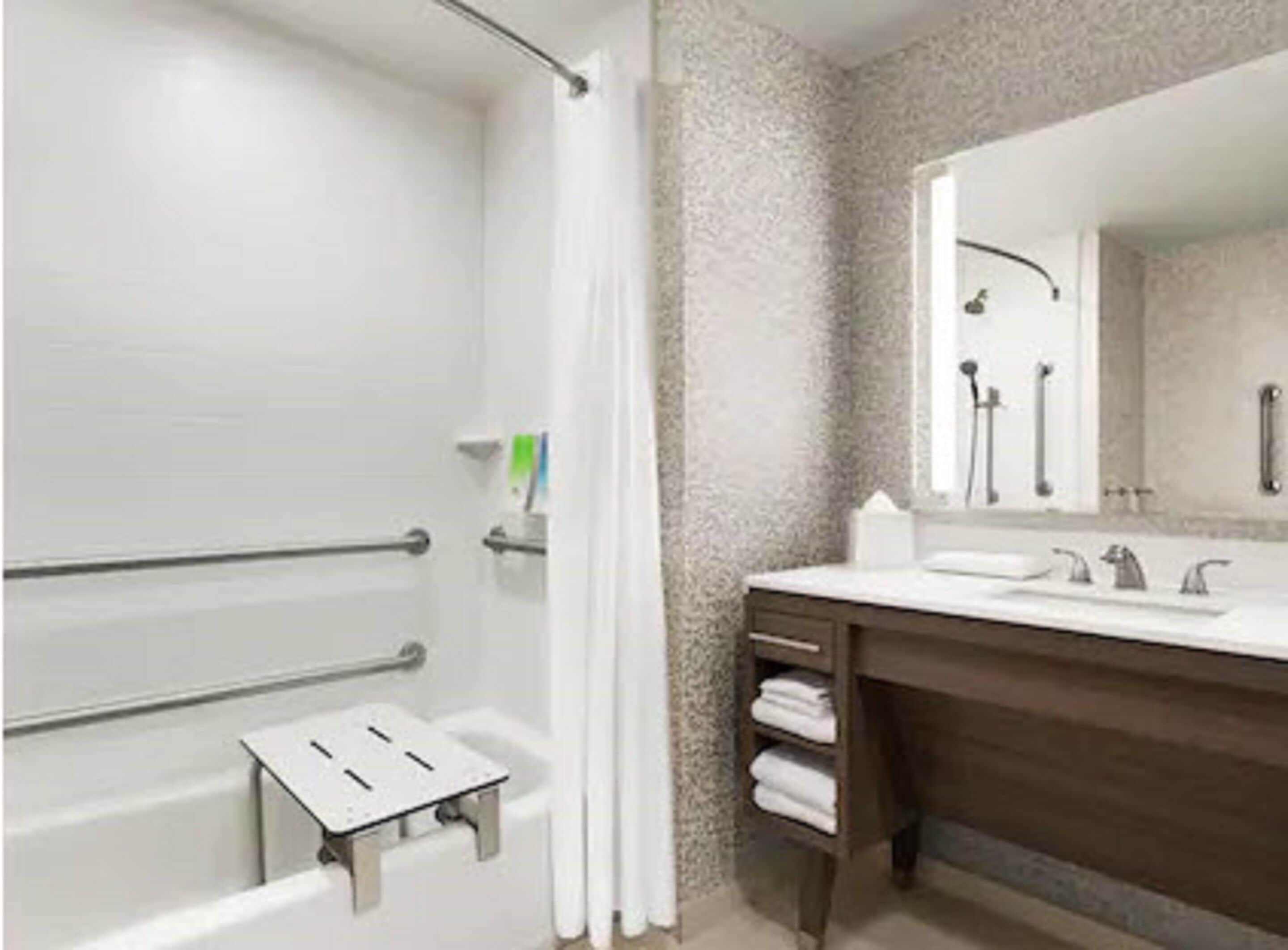 Un baño con ducha, tocador con espejo y perchero.