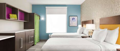 A hotel room with a bed, a desk, a chair, a nightstand, and a window.